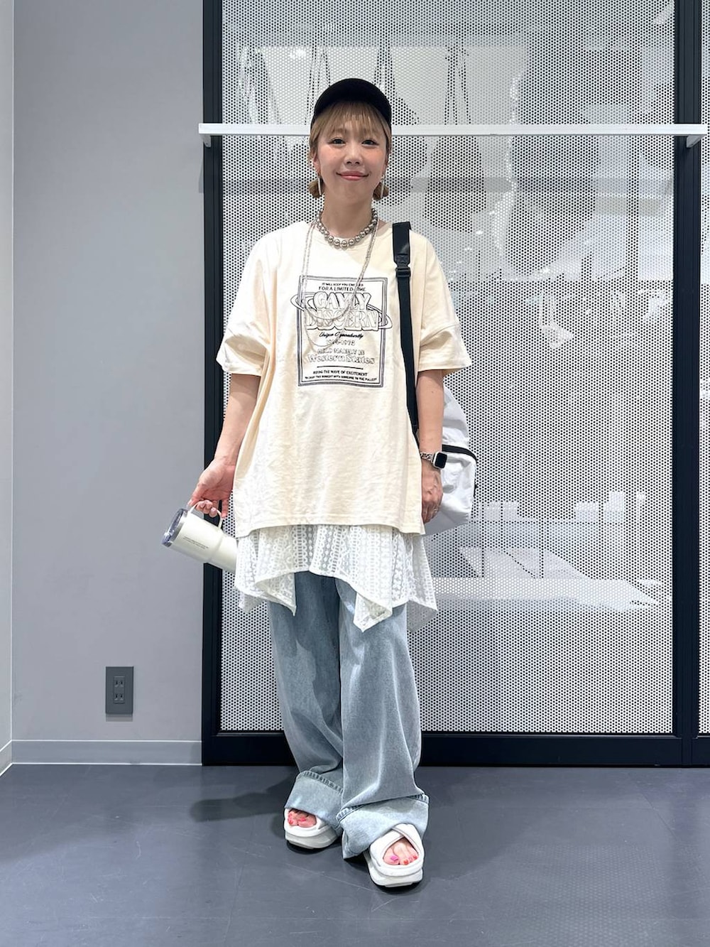 ホワイト系のショルダーバッグ、ブルー系のデニムパンツ、ベージュ系のワンピースを着用したレディースの夏コーディネートの2枚目の写真