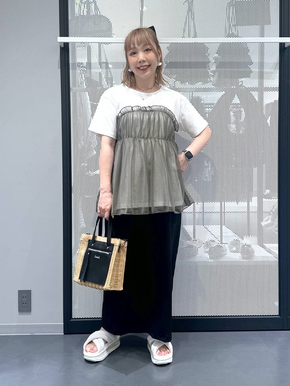 ベージュ系のショルダーバッグ、ブラック系のスカート、グリーン系のTシャツ/カットソーを着用したレディースの春コーディネートの5枚目の写真