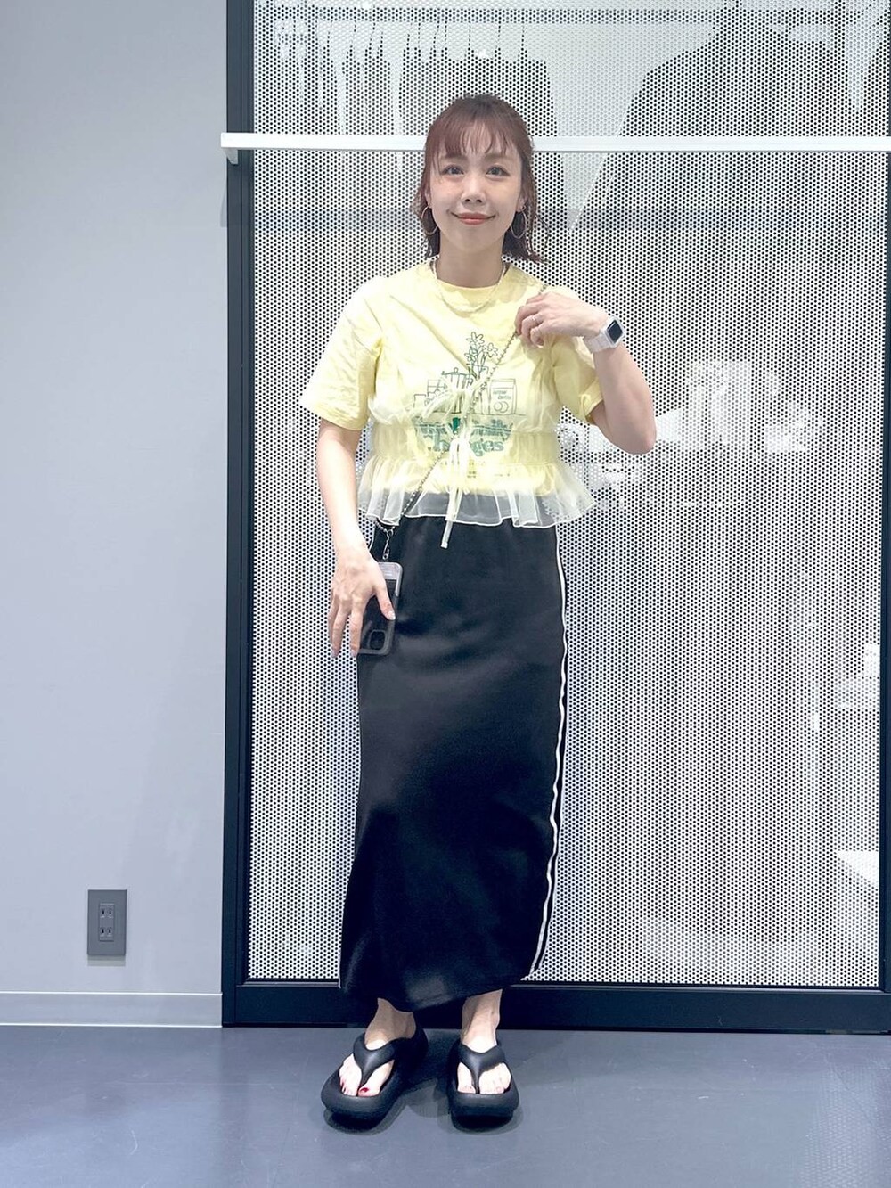 ブラック系のスカート、イエロー系のキャミソール、ベージュ系のTシャツ/カットソーを着用したレディースの春コーディネートの2枚目の写真