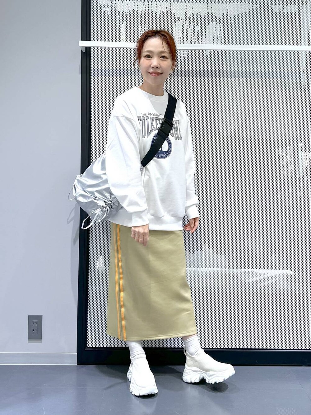 グリーン系のスカート、シルバー系のショルダーバッグ、ブラック系のシュシュを着用したレディースの冬コーディネートの2枚目の写真