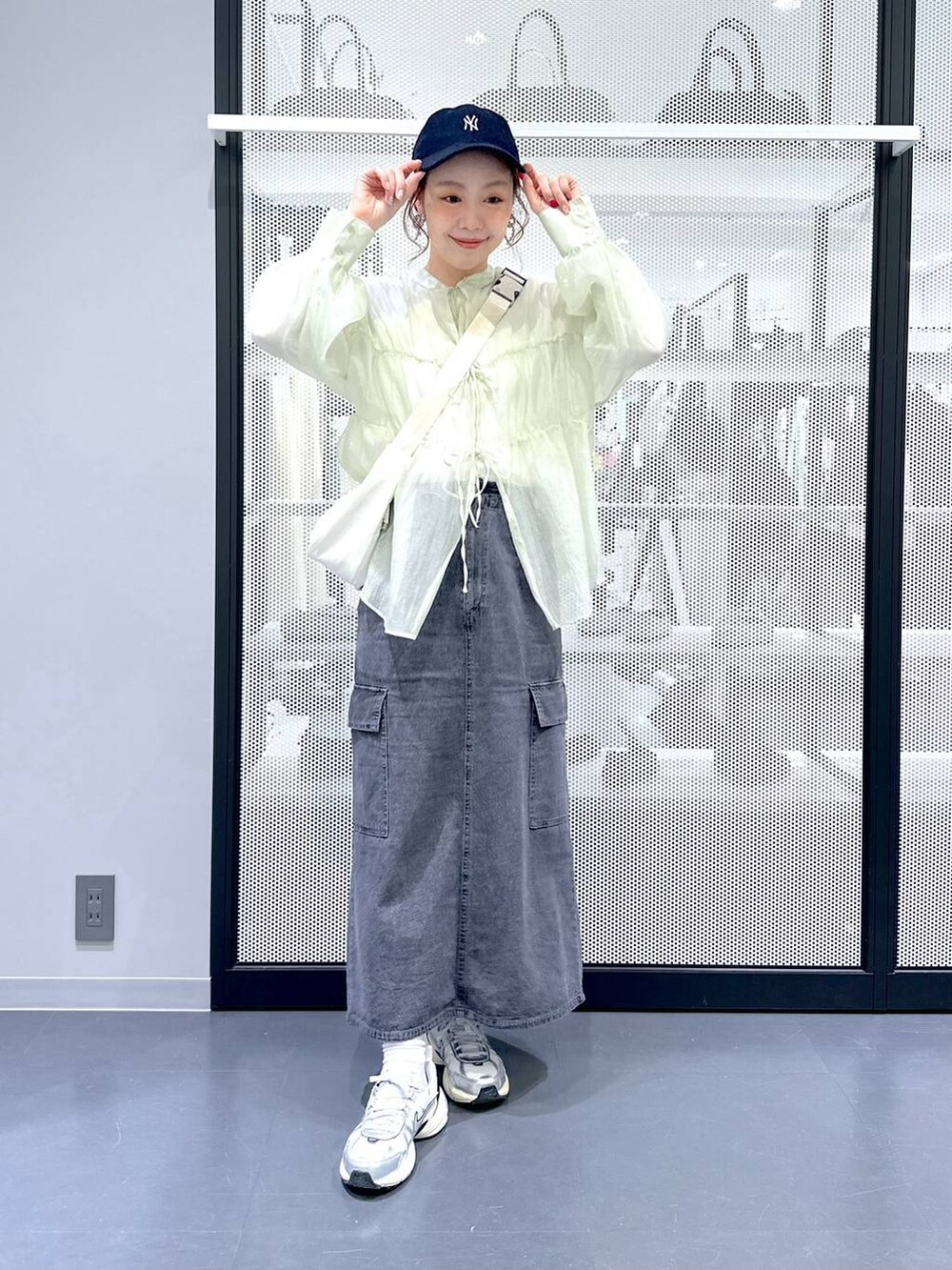 グレー系のデニムスカート、ホワイト系のTシャツ/カットソー、ホワイト系のショルダーバッグを着用したレディースの春コーディネートの8枚目の写真