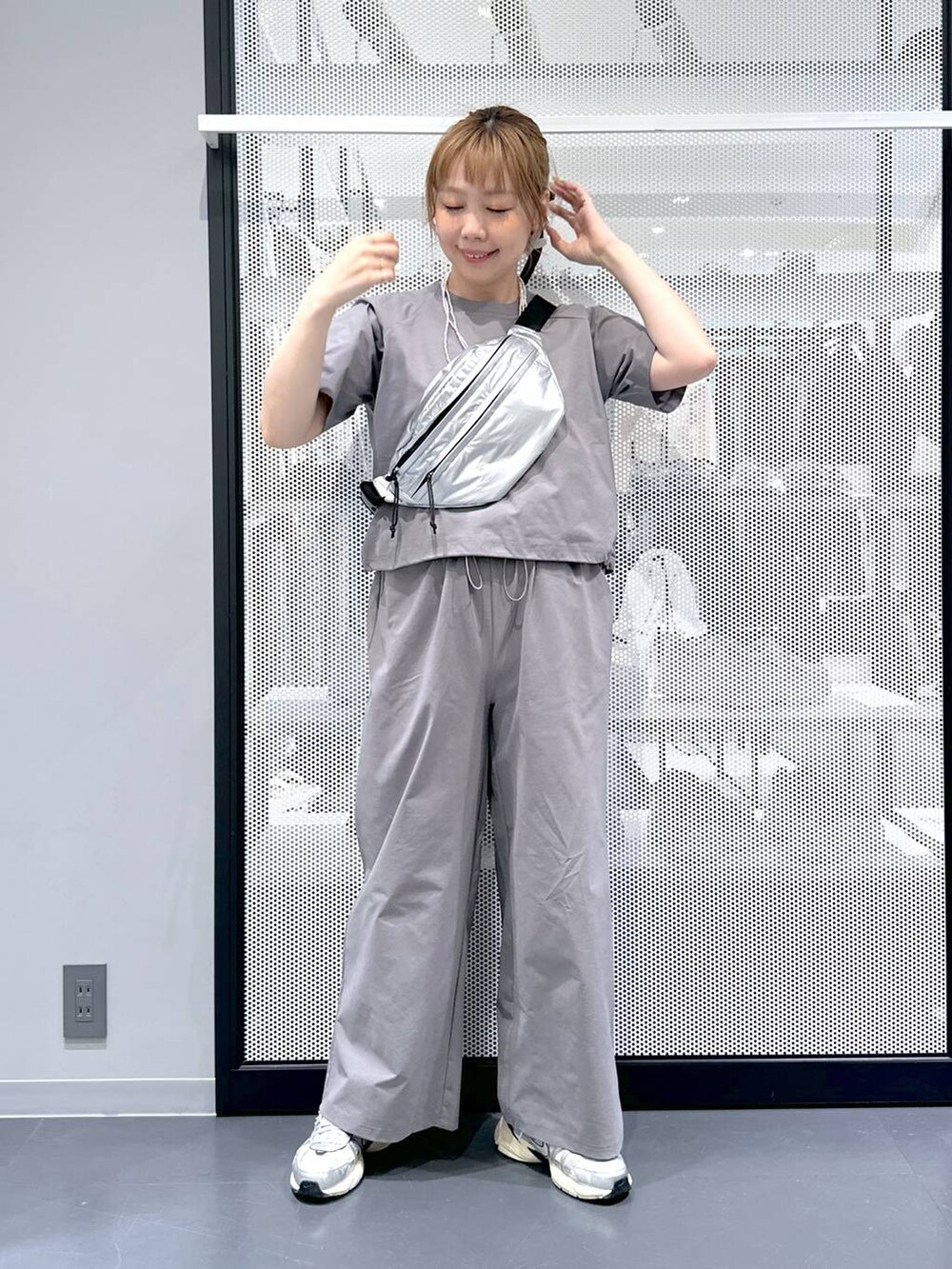 シルバー系のボディバッグ/ウエストポーチ、グレー系のTシャツ/カットソー、グレー系のその他パンツを着用したレディースの春コーディネートの2枚目の写真