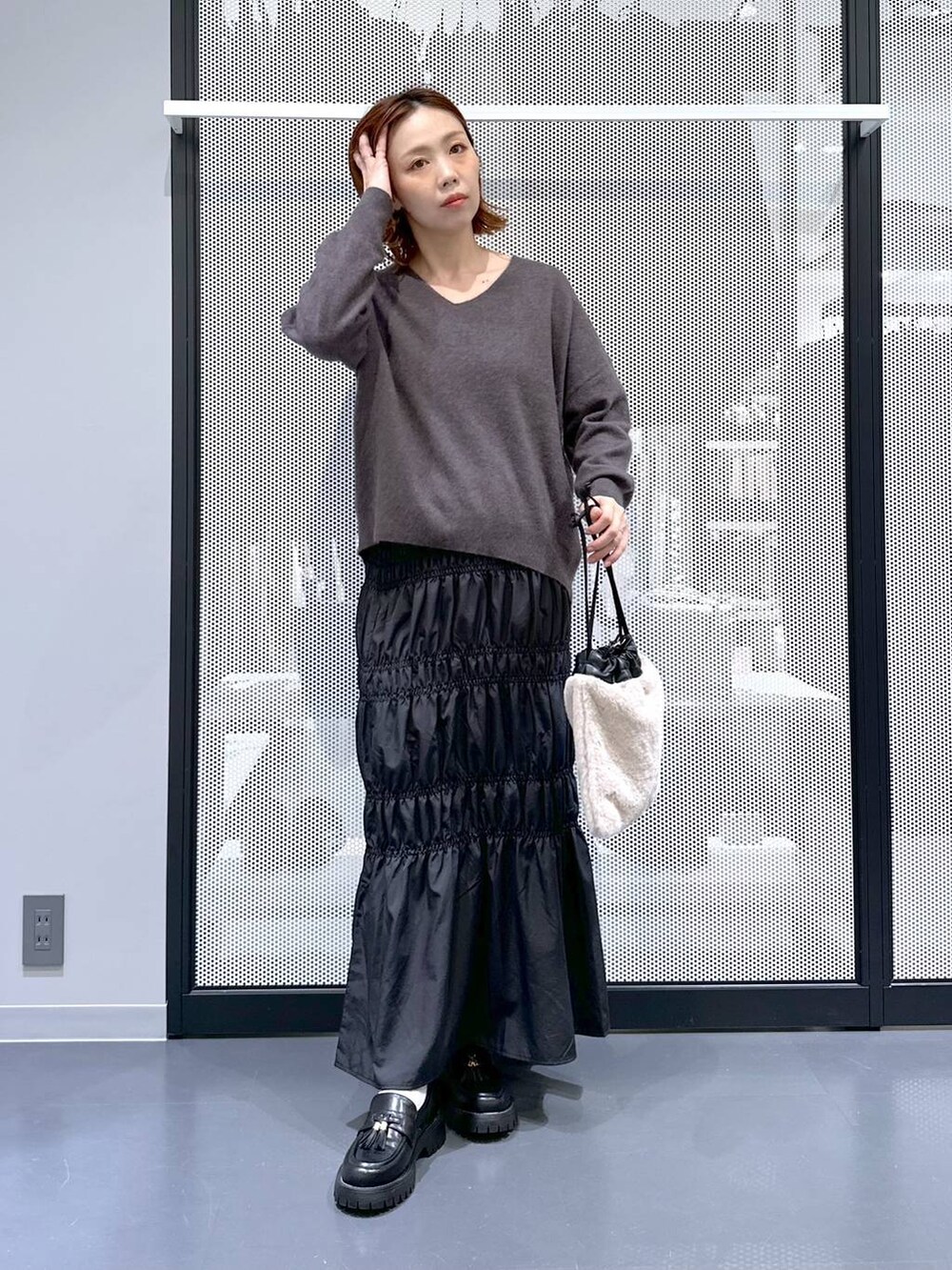 グレー系のニット/セーター、ブラック系のナイロンジャケット、ベージュ系のショルダーバッグを着用したレディースの冬コーディネートの7枚目の写真