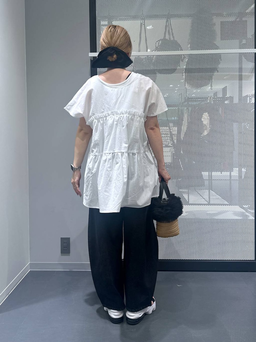 ブラック系のデニムパンツ、ベージュ系のショルダーバッグ、ホワイト系のタンクトップを着用したレディースの夏コーディネートの2枚目の写真