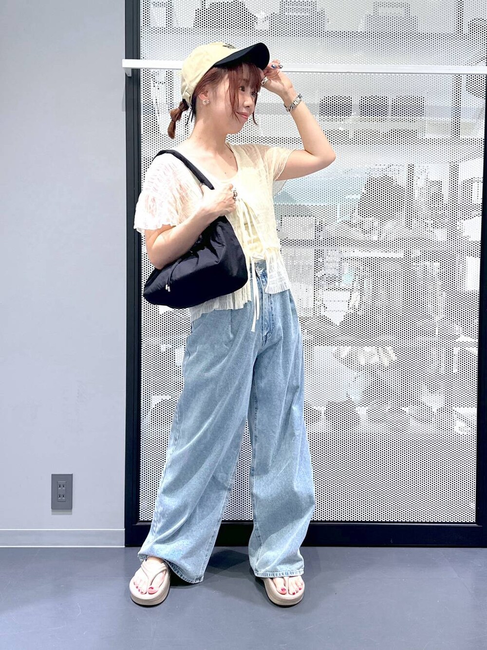 ブルー系のデニムパンツ、ブラック系のハンドバッグ、ベージュ系のサンダルを着用したレディースの夏コーディネートの7枚目の写真