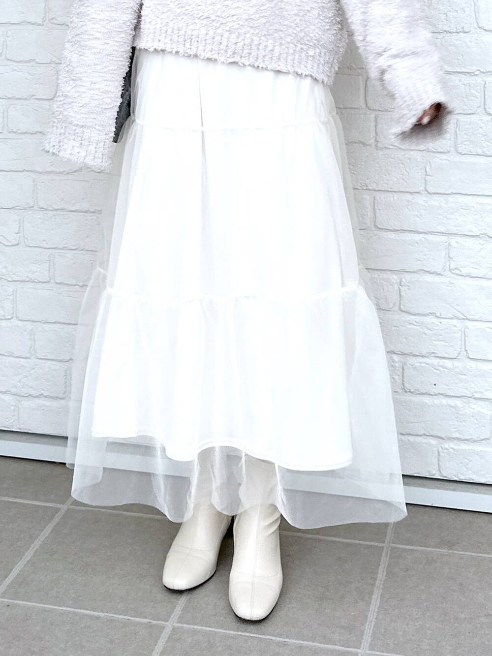 グレー系のニット/セーター、ホワイト系のブーツ、ホワイト系のTシャツ/カットソーを着用したレディースの冬コーディネートの5枚目の写真