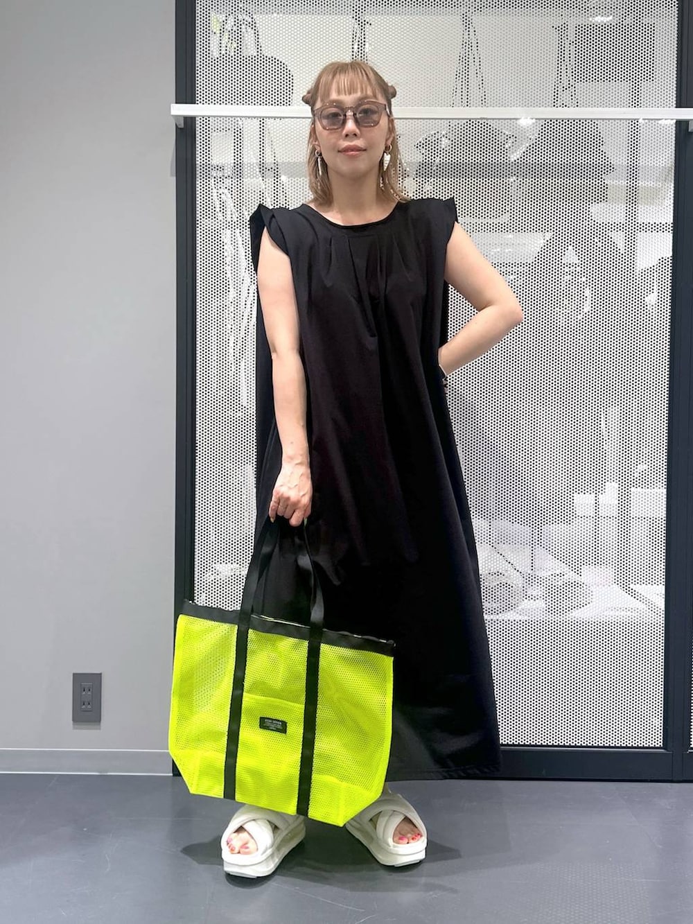 ブラック系のワンピース、イエロー系のトートバッグ、ホワイト系のサンダルを着用したレディースの春コーディネートの2枚目の写真