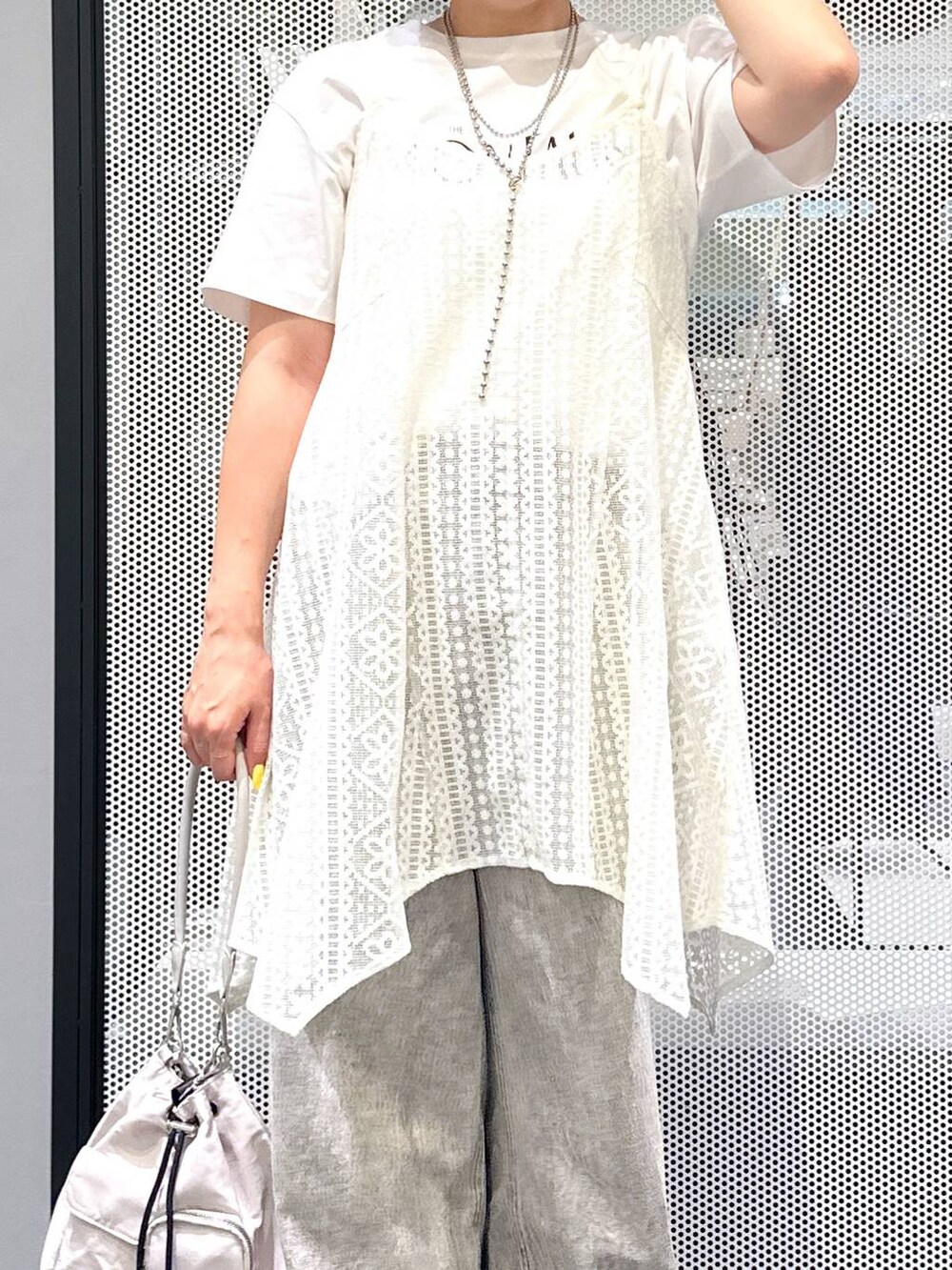 グレー系のデニムパンツ、ブラック系のサンダル、ホワイト系のショルダーバッグを着用したレディースの夏コーディネートの2枚目の写真