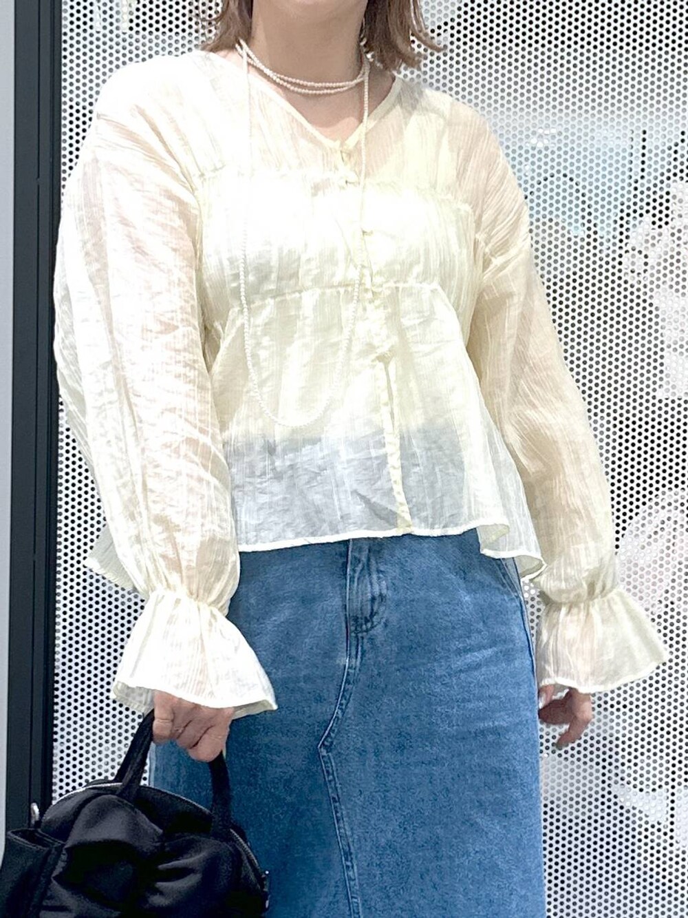 ブルー系のデニムスカート、ベージュ系のシャツ/ブラウス、ブラック系のショルダーバッグを着用したレディースの春コーディネートの4枚目の写真