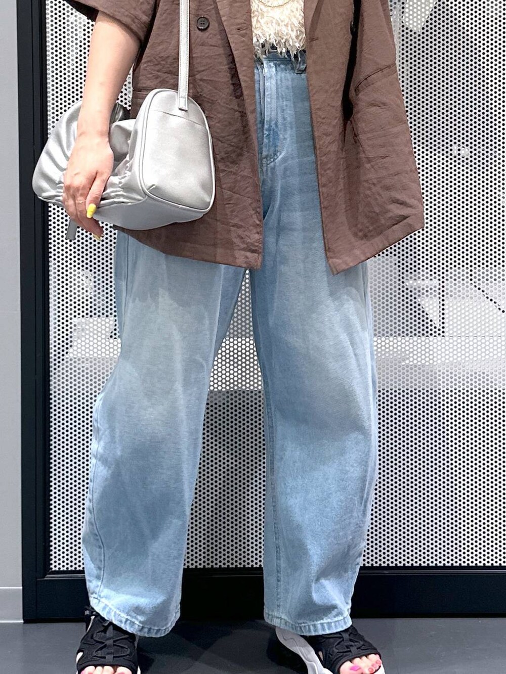 ブルー系のデニムパンツ、シルバー系のショルダーバッグ、ホワイト系のベストを着用したレディースの夏コーディネートの5枚目の写真