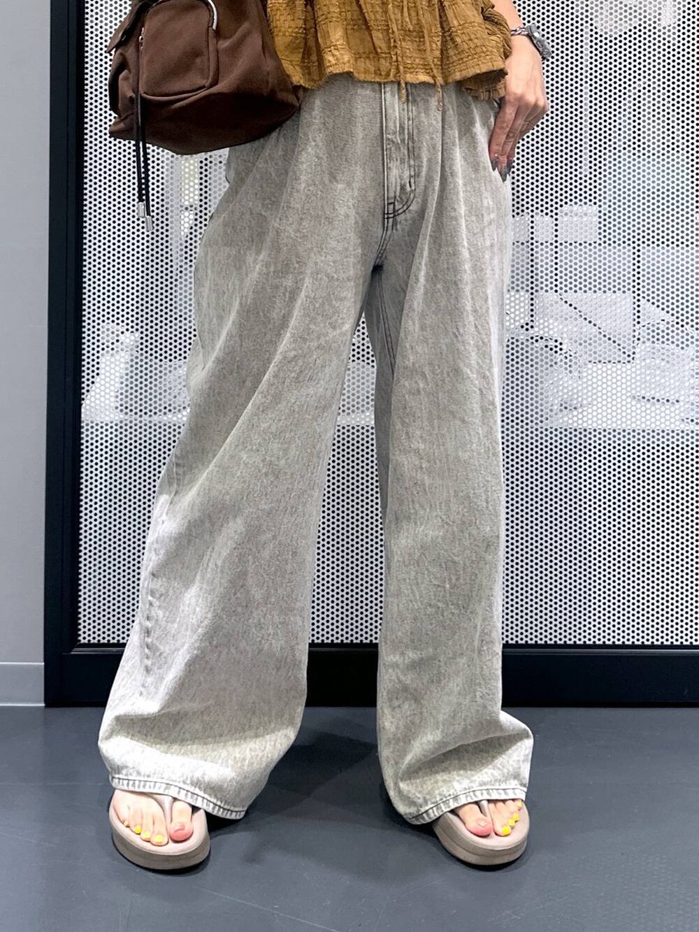 グレー系のデニムパンツ、ホワイト系のTシャツ/カットソー、ベージュ系のサンダルを着用したレディースの夏コーディネートの5枚目の写真