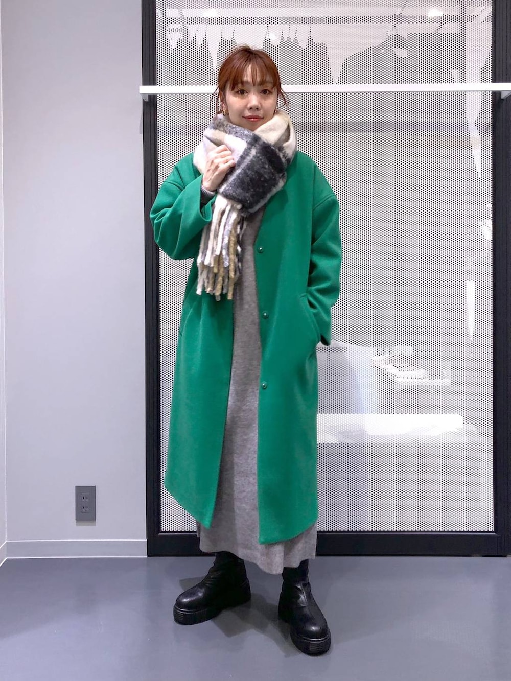 ブラック系のブーツ、シルバー系のショルダーバッグ、グリーン系のノーカラーコートを着用したレディースの冬コーディネートの5枚目の写真