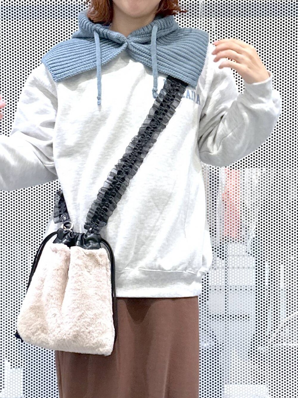 ベージュ系のショルダーバッグ、ブラウン系のスカート、ブラック系のブーツを着用したレディースの冬コーディネートの4枚目の写真