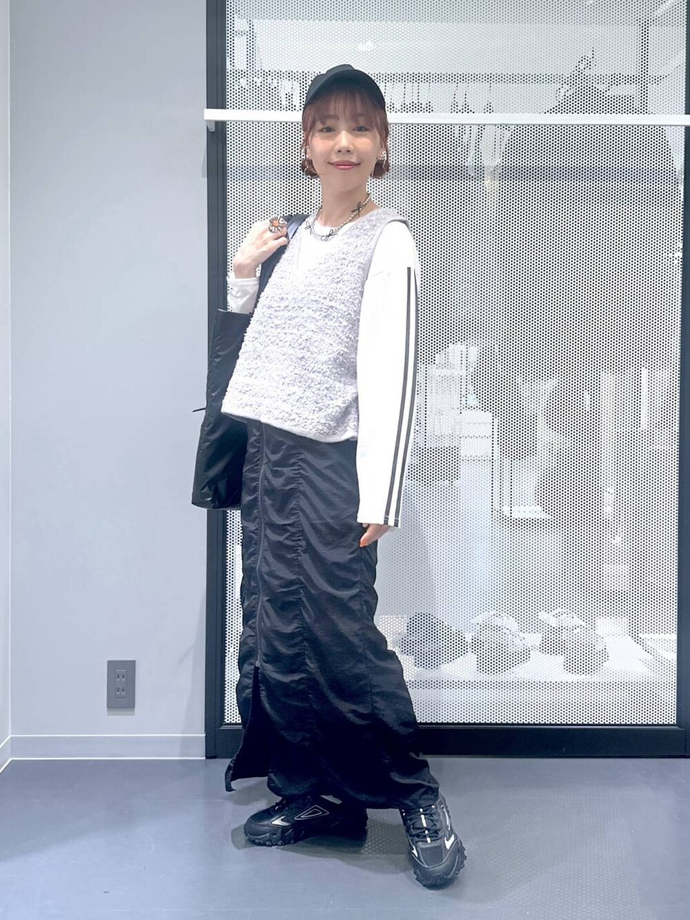 グレー系のスニーカー、ホワイト系のTシャツ/カットソー、グレー系のベストを着用したレディースの秋コーディネートの7枚目の写真