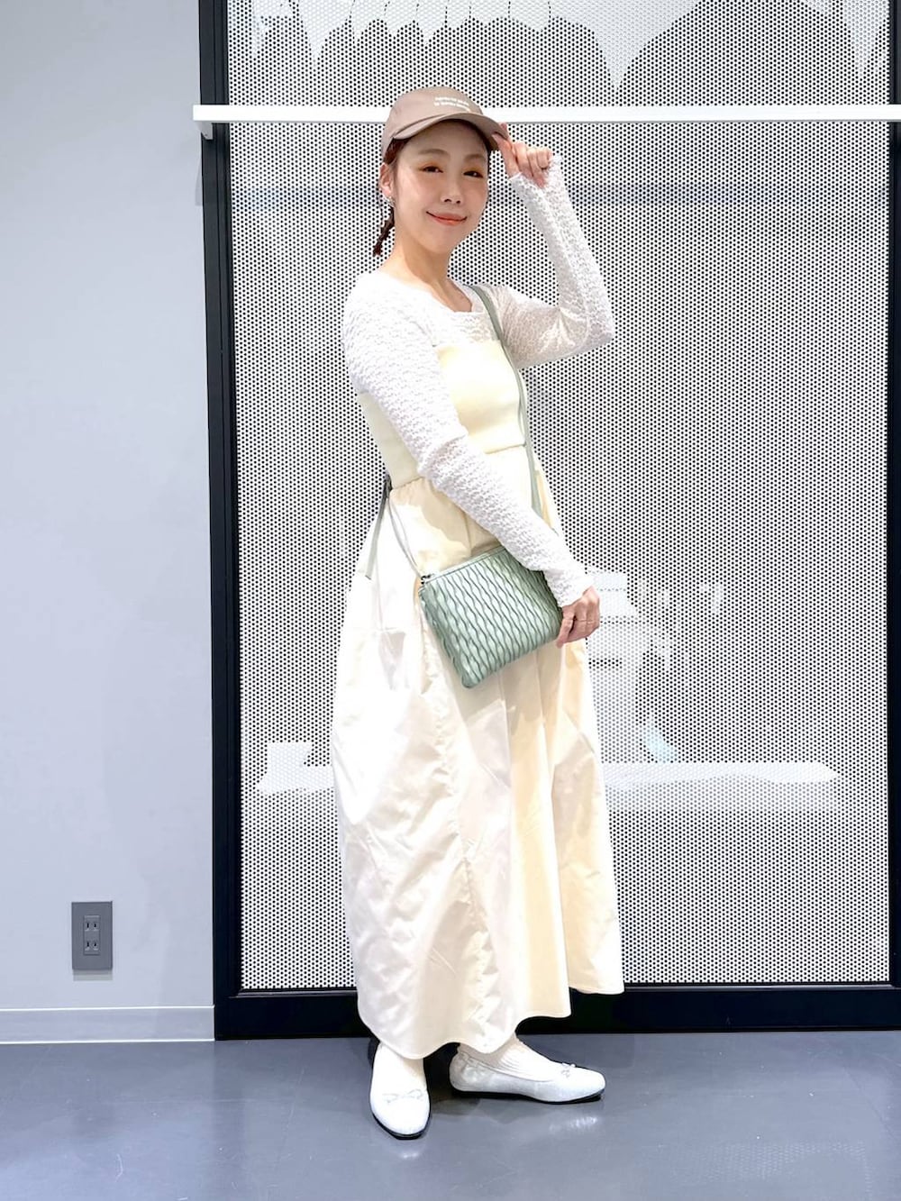 グリーン系のショルダーバッグ、シルバー系のバレエシューズ、ホワイト系のTシャツ/カットソーを着用したレディースの春コーディネートの2枚目の写真