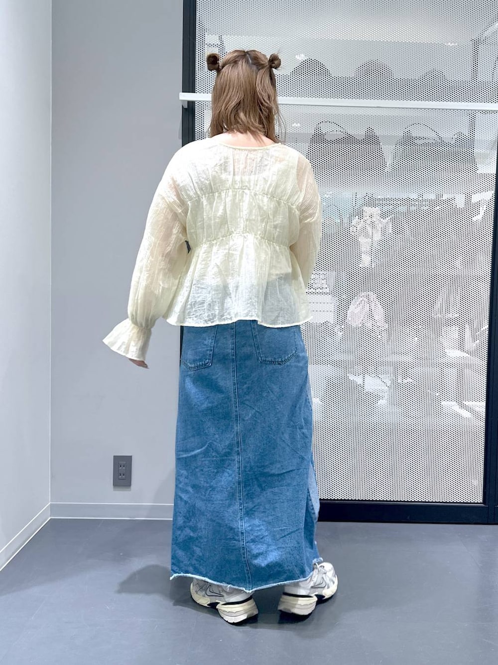 ブルー系のデニムスカート、ベージュ系のシャツ/ブラウス、ブラック系のショルダーバッグを着用したレディースの春コーディネートの3枚目の写真