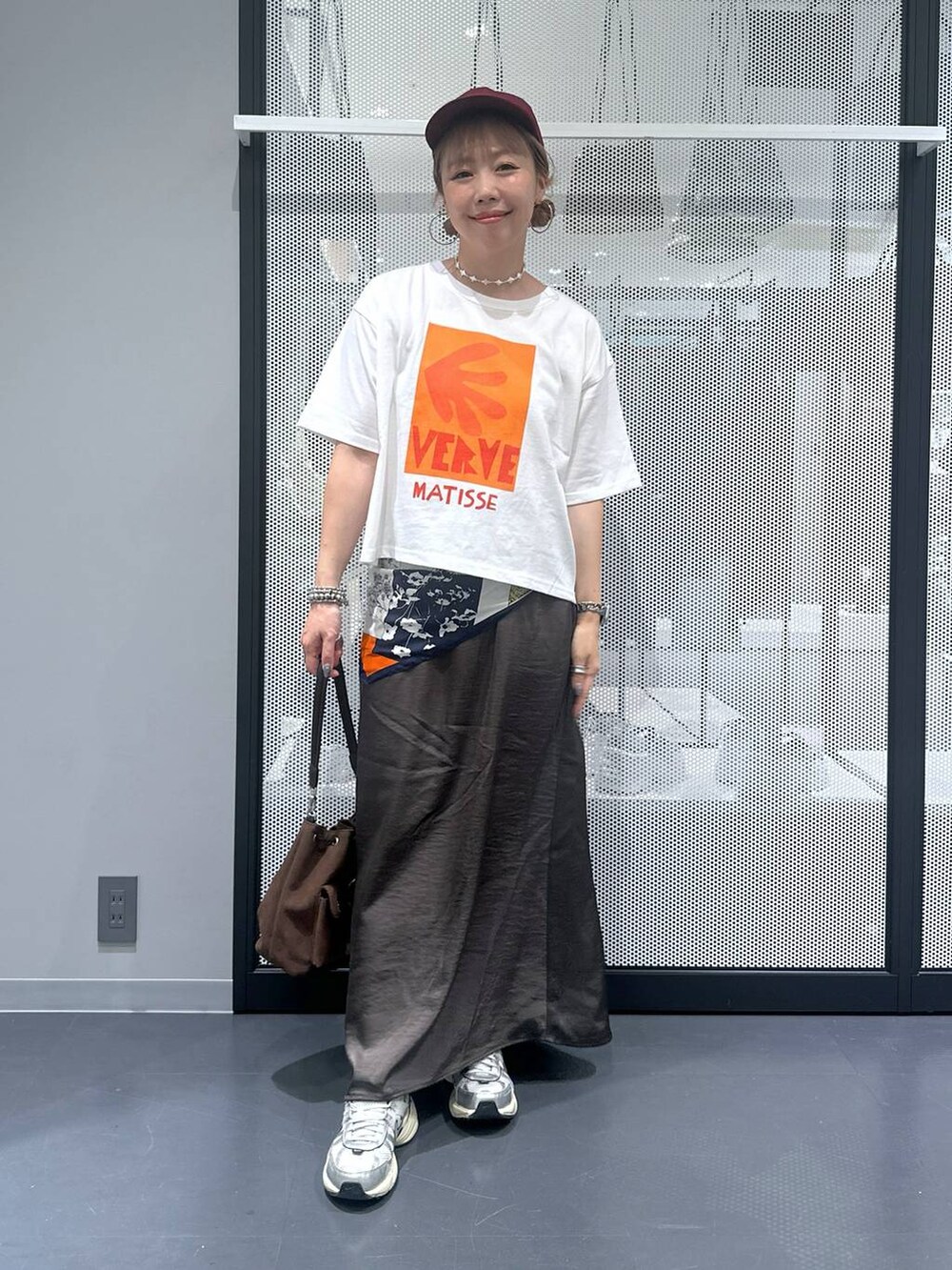 ブラウン系のショルダーバッグ、グレー系のスカート、その他のピアス（両耳用）を着用したレディースの夏コーディネートの2枚目の写真