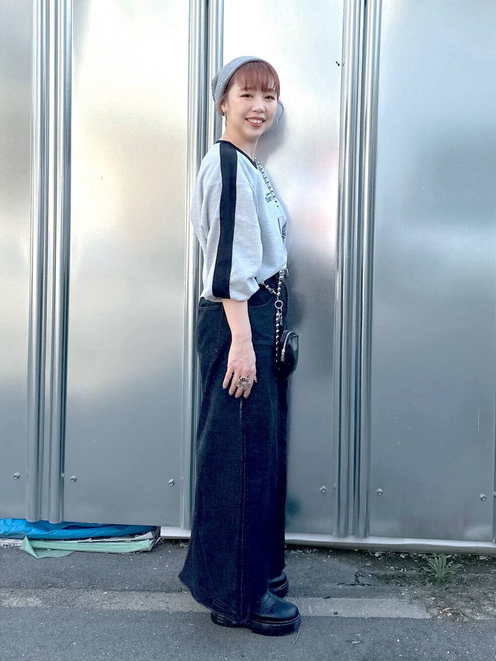 ブラック系のデニムスカート、グレー系のTシャツ/カットソー、ブラック系のブーツを着用したレディースの秋コーディネートの6枚目の写真