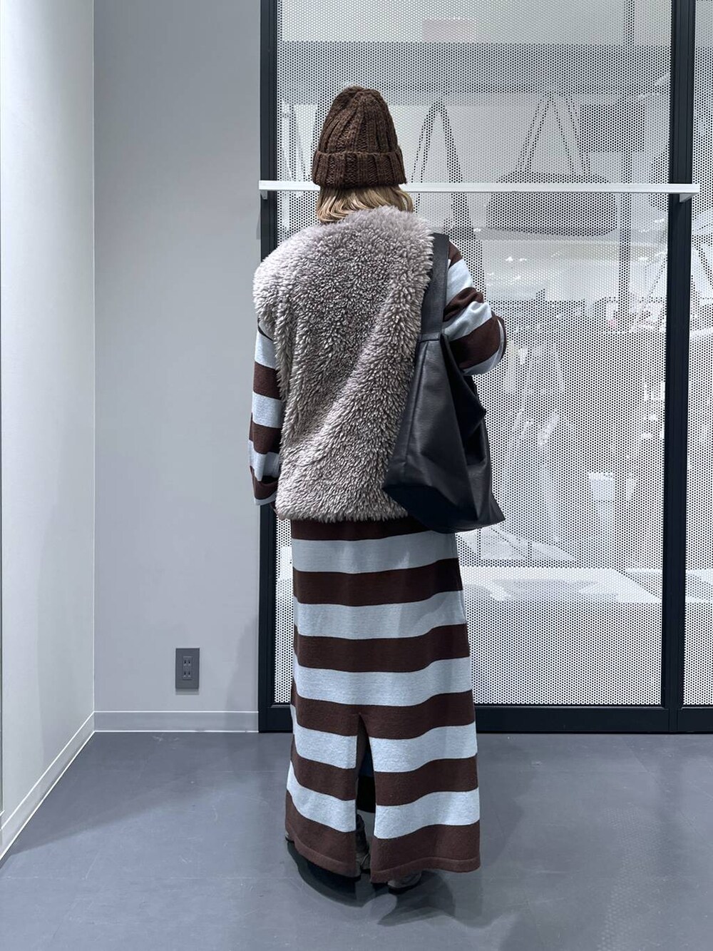 ブラック系のショルダーバッグ、グレー系のベスト、ブラウン系のワンピースを着用したレディースの秋コーディネートの2枚目の写真