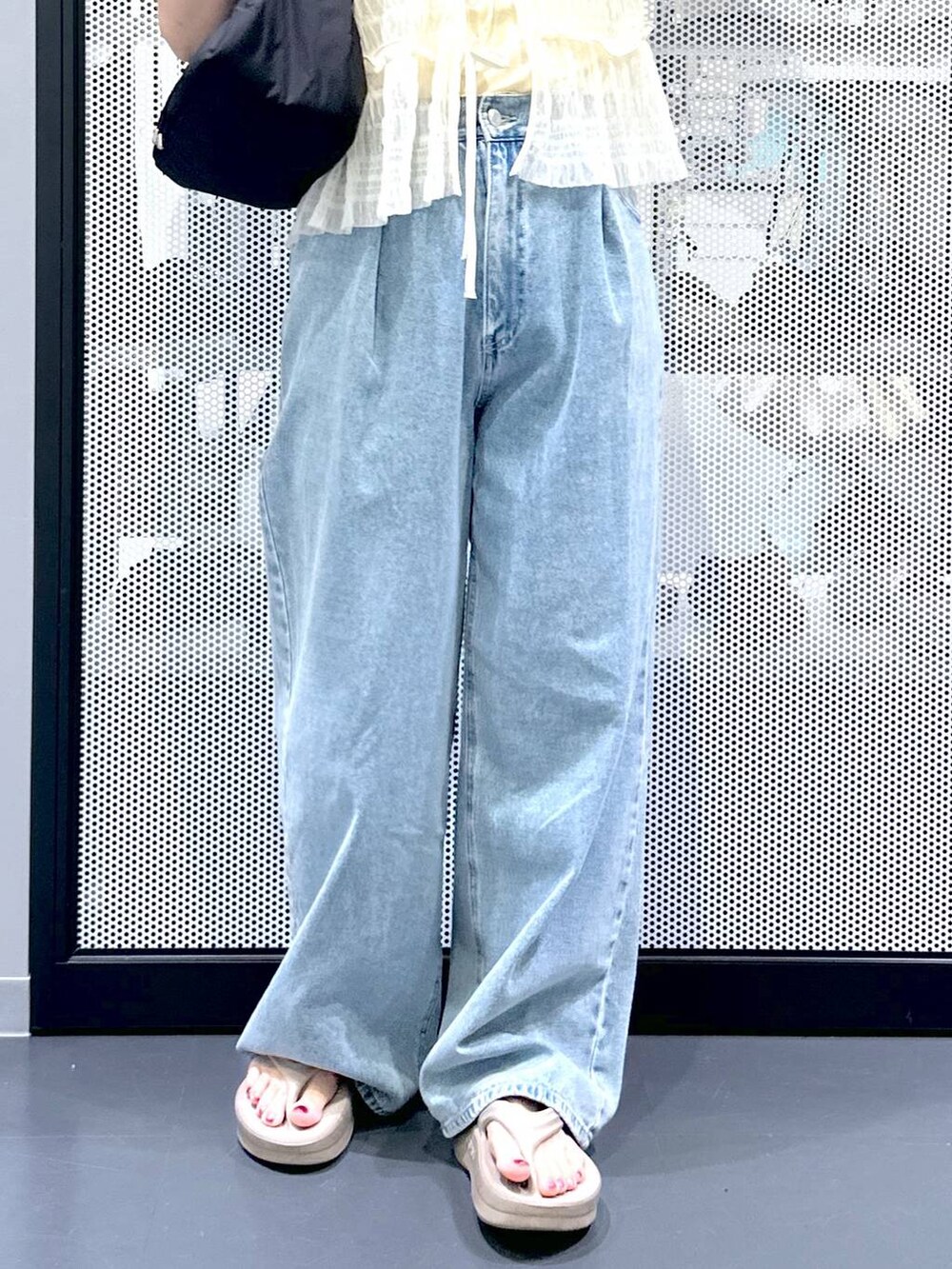 ブルー系のデニムパンツ、ブラック系のハンドバッグ、ベージュ系のサンダルを着用したレディースの夏コーディネートの6枚目の写真