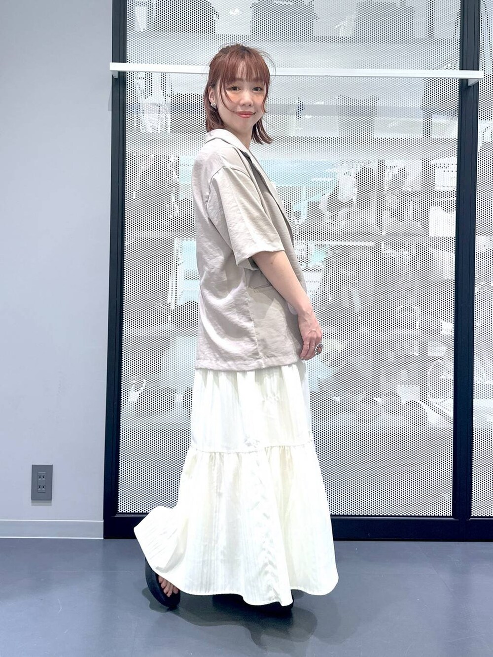 ブラック系のショルダーバッグ、ベージュ系のワンピース、ベージュ系のTシャツ/カットソーを着用したレディースの夏コーディネートの2枚目の写真