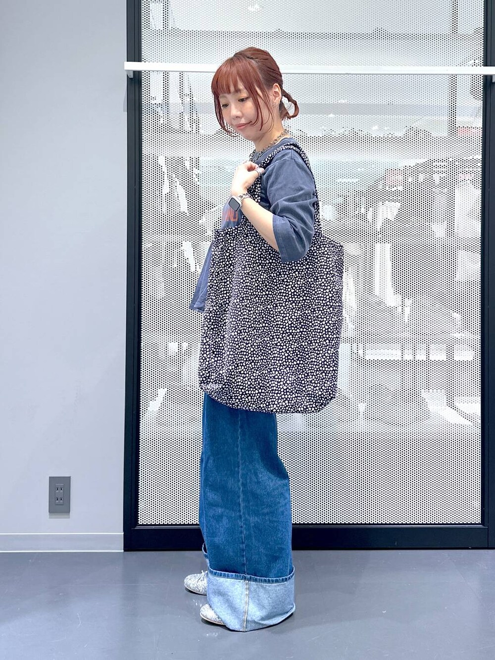 ブラック系のトートバッグ、シルバー系のパンプス、ブルー系のデニムパンツを着用したレディースの夏コーディネートの3枚目の写真