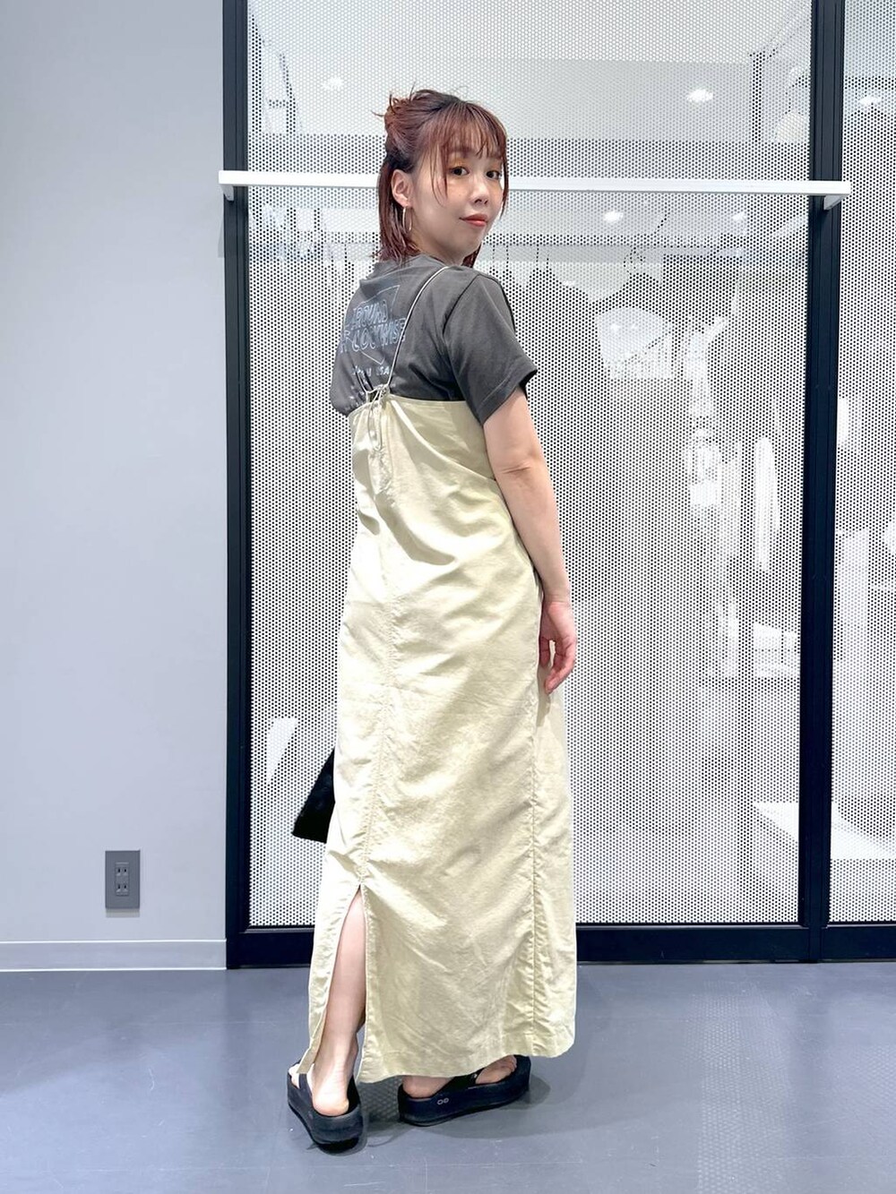 ベージュ系のワンピース、ブラック系のサンダル、グレー系のTシャツ/カットソーを着用したレディースの春コーディネートの6枚目の写真