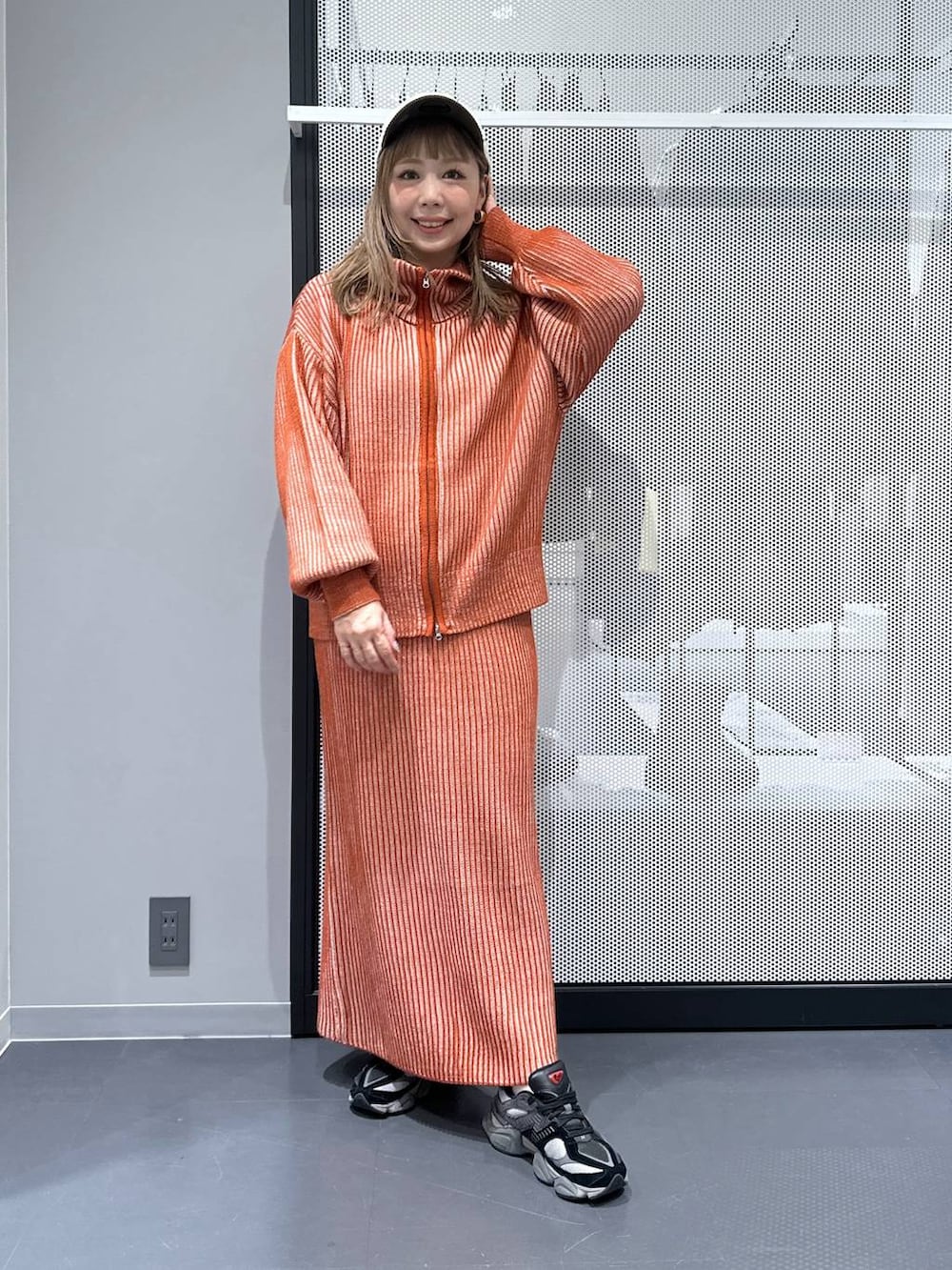 オレンジ系のスカート、オレンジ系のニット/セーター、その他のピアス（両耳用）を着用したレディースの冬コーディネートの3枚目の写真