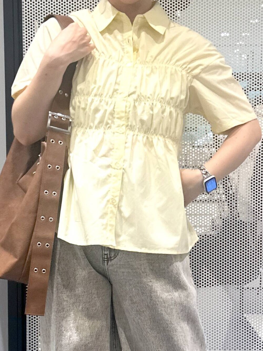 グレー系のデニムパンツ、ブラウン系のショルダーバッグ、イエロー系のシャツ/ブラウスを着用したレディースの夏コーディネートの2枚目の写真