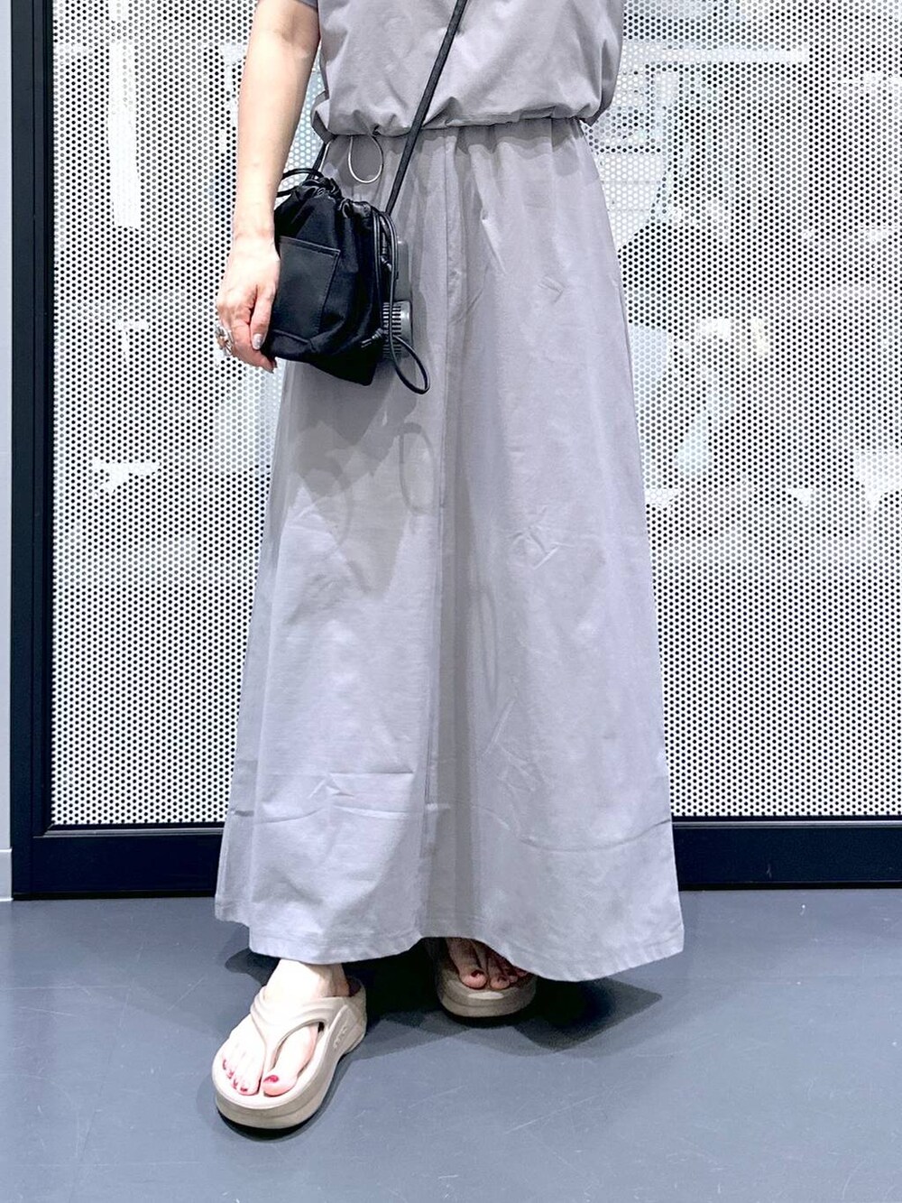 ブラック系のショルダーバッグ、ベージュ系のサンダル、グレー系のTシャツ/カットソーを着用したレディースの夏コーディネートの5枚目の写真