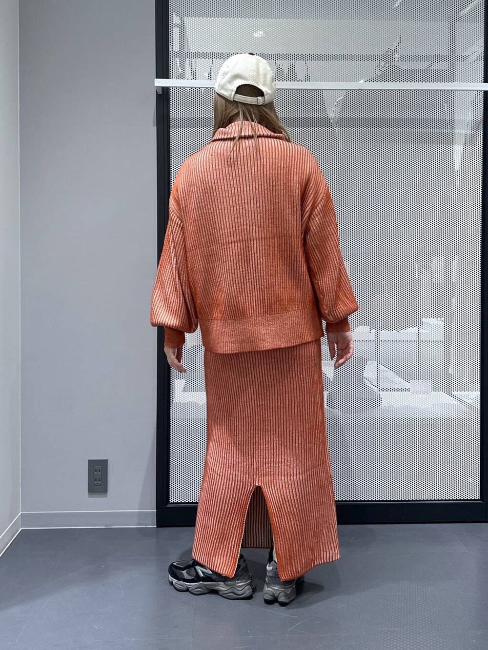 オレンジ系のスカート、オレンジ系のニット/セーター、その他のピアス（両耳用）を着用したレディースの冬コーディネートの2枚目の写真