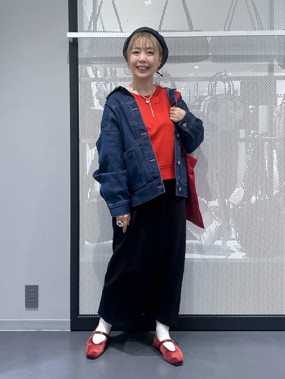 ブラック系のスカート、レッド系のトートバッグ、レッド系のパンプスを着用したレディースの秋コーディネートの2枚目の写真