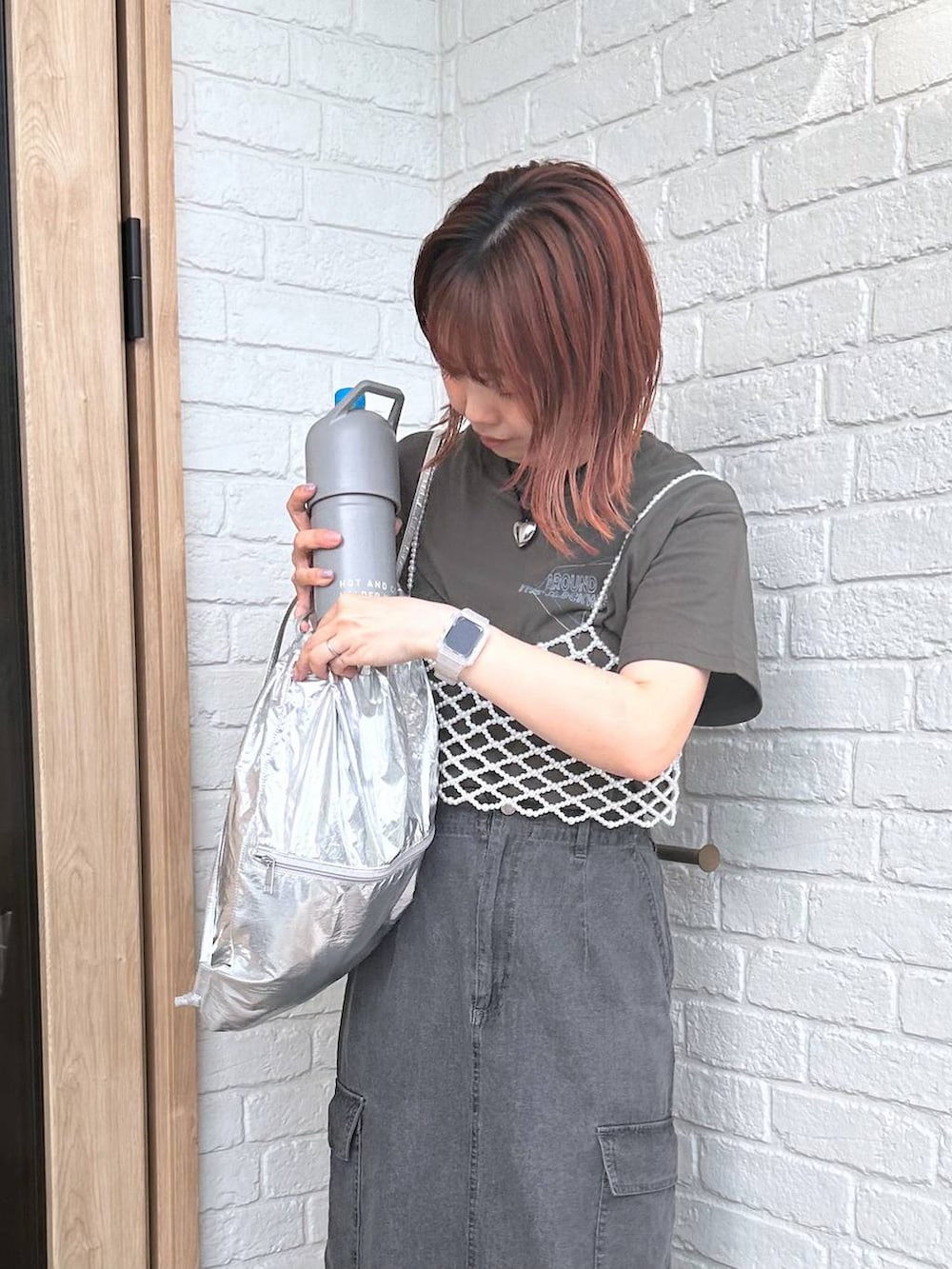 グレー系のデニムスカート、シルバー系のバックパック/リュック、ブラック系のサンダルを着用したレディースの春コーディネートの3枚目の写真