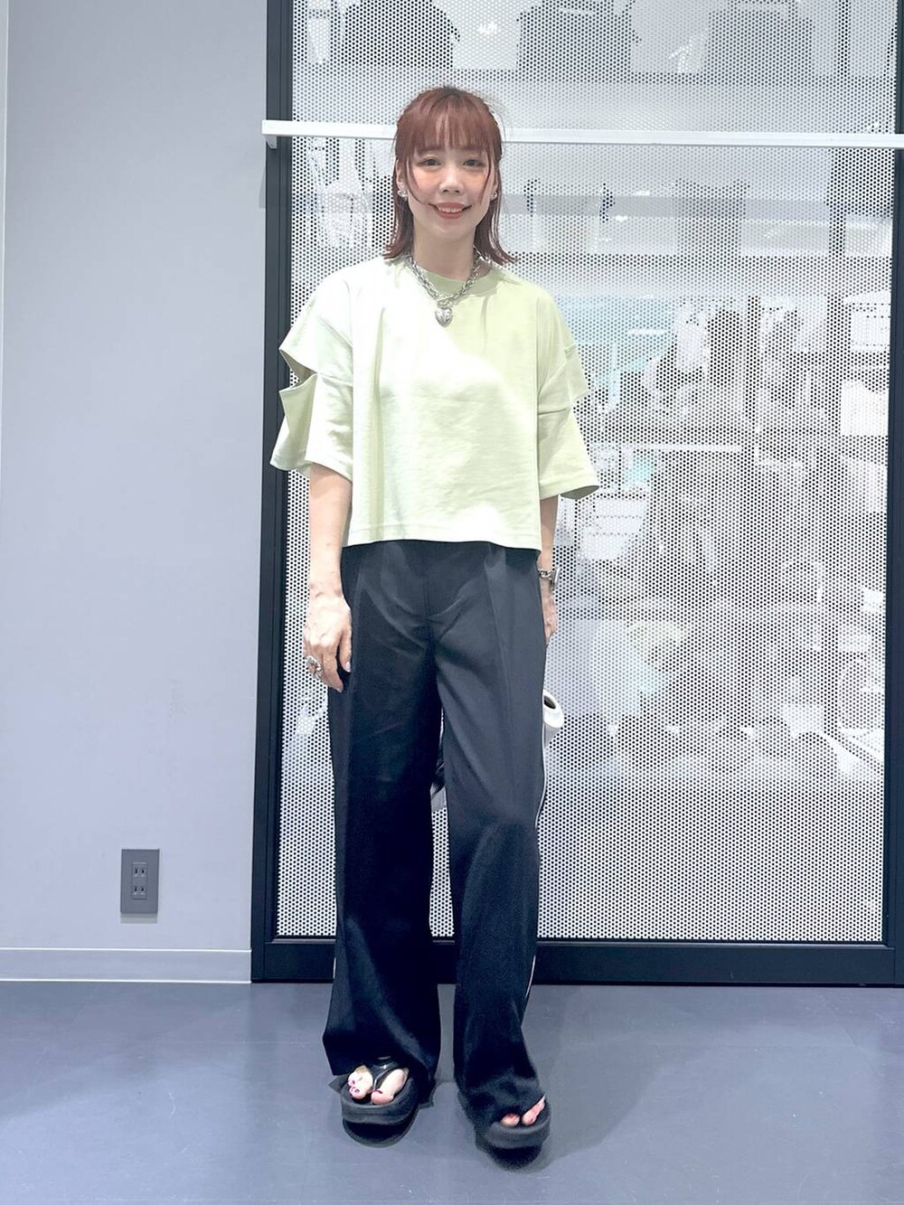 シルバー系のショルダーバッグ、グリーン系のTシャツ/カットソー、ブラック系のサンダルを着用したレディースの夏コーディネートの2枚目の写真