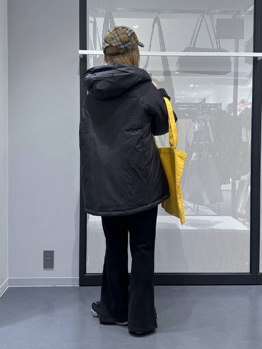 イエロー系のトートバッグ、ブラック系のダウンジャケット/コート、ブラック系のその他パンツを着用したレディースの冬コーディネートの5枚目の写真