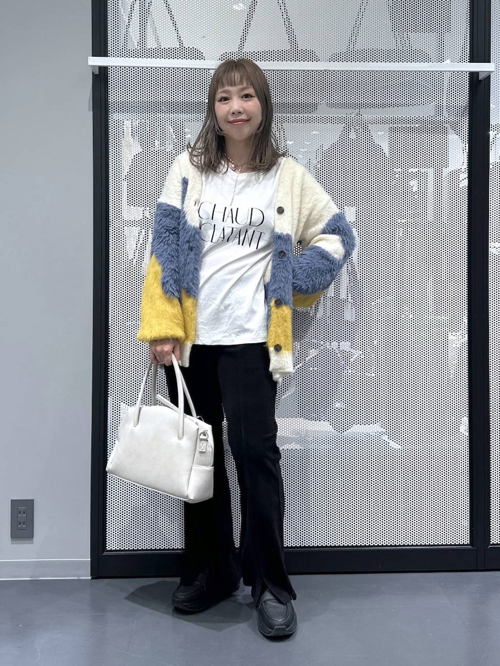 グレー系のボストンバッグ、イエロー系のカーディガン/ボレロ、ホワイト系のTシャツ/カットソーを着用したレディースの秋コーディネートの6枚目の写真