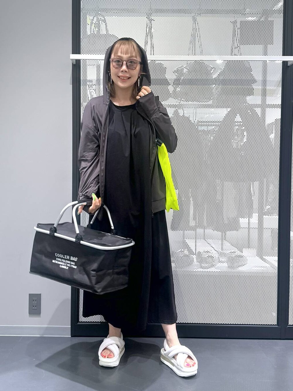 ブラック系のワンピース、イエロー系のトートバッグ、ホワイト系のサンダルを着用したレディースの春コーディネートの5枚目の写真