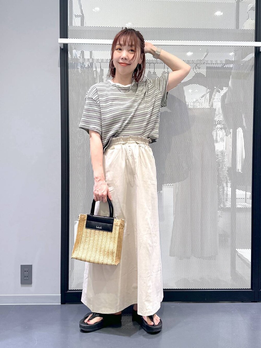 ベージュ系のスカート、ブラック系のサンダル、ベージュ系のショルダーバッグを着用したレディースの夏コーディネートの2枚目の写真