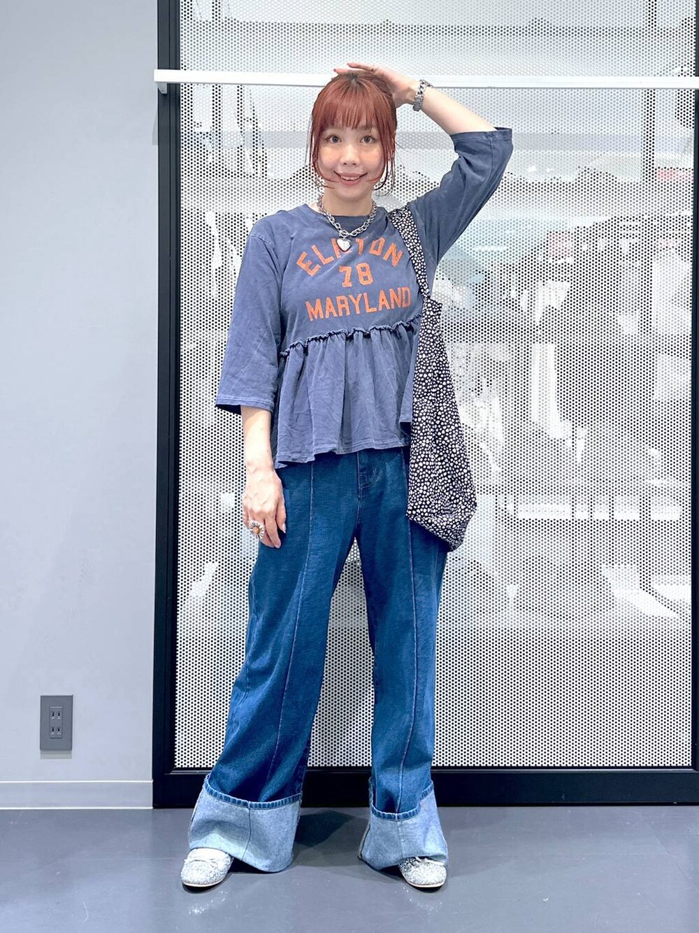 ブラック系のトートバッグ、シルバー系のパンプス、ブルー系のデニムパンツを着用したレディースの夏コーディネートの2枚目の写真