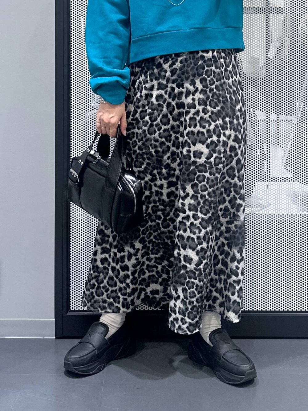 ブラック系のショルダーバッグ、グレー系のスカート、ブルー系のスウェットを着用したレディースの秋コーディネートの5枚目の写真