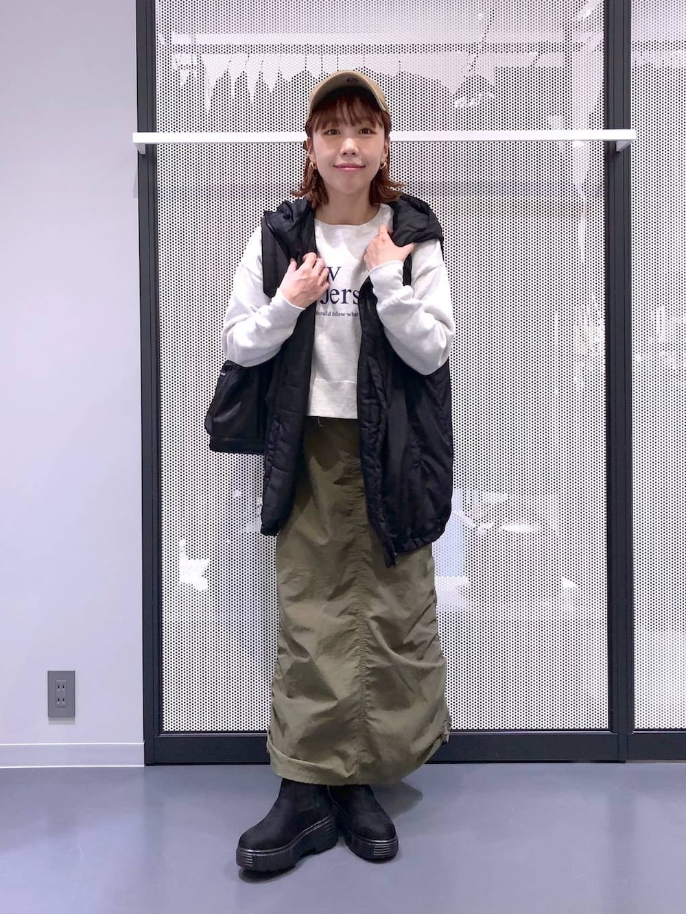 ブラック系のバックパック/リュック、グリーン系のスカート、ブラック系のベストを着用したレディースの冬コーディネートの6枚目の写真