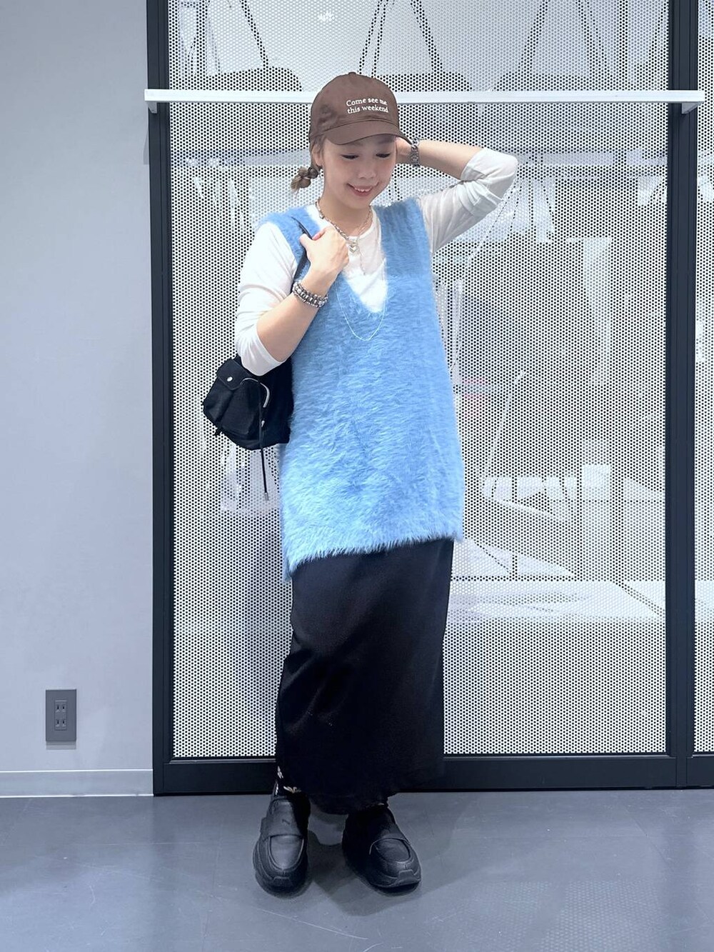 ホワイト系のTシャツ/カットソー、ブラック系のスカート、ブルー系のベストを着用したレディースの秋コーディネートの2枚目の写真