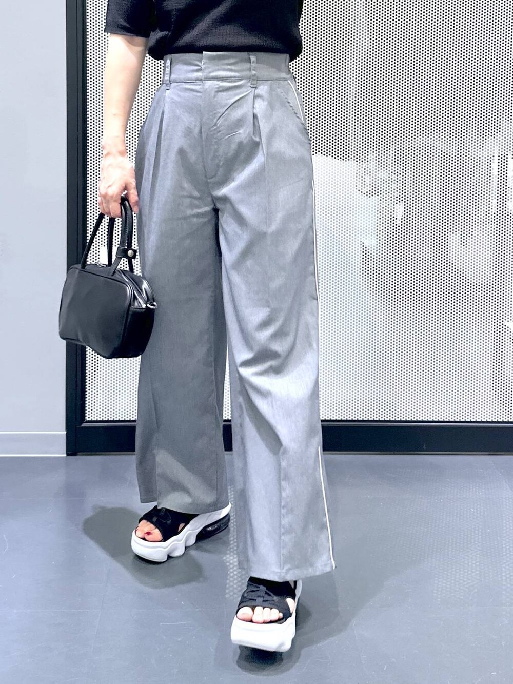 ブラック系のショルダーバッグ、ブラック系のカーディガン/ボレロ、グレー系のスラックスを着用したレディースの夏コーディネートの7枚目の写真