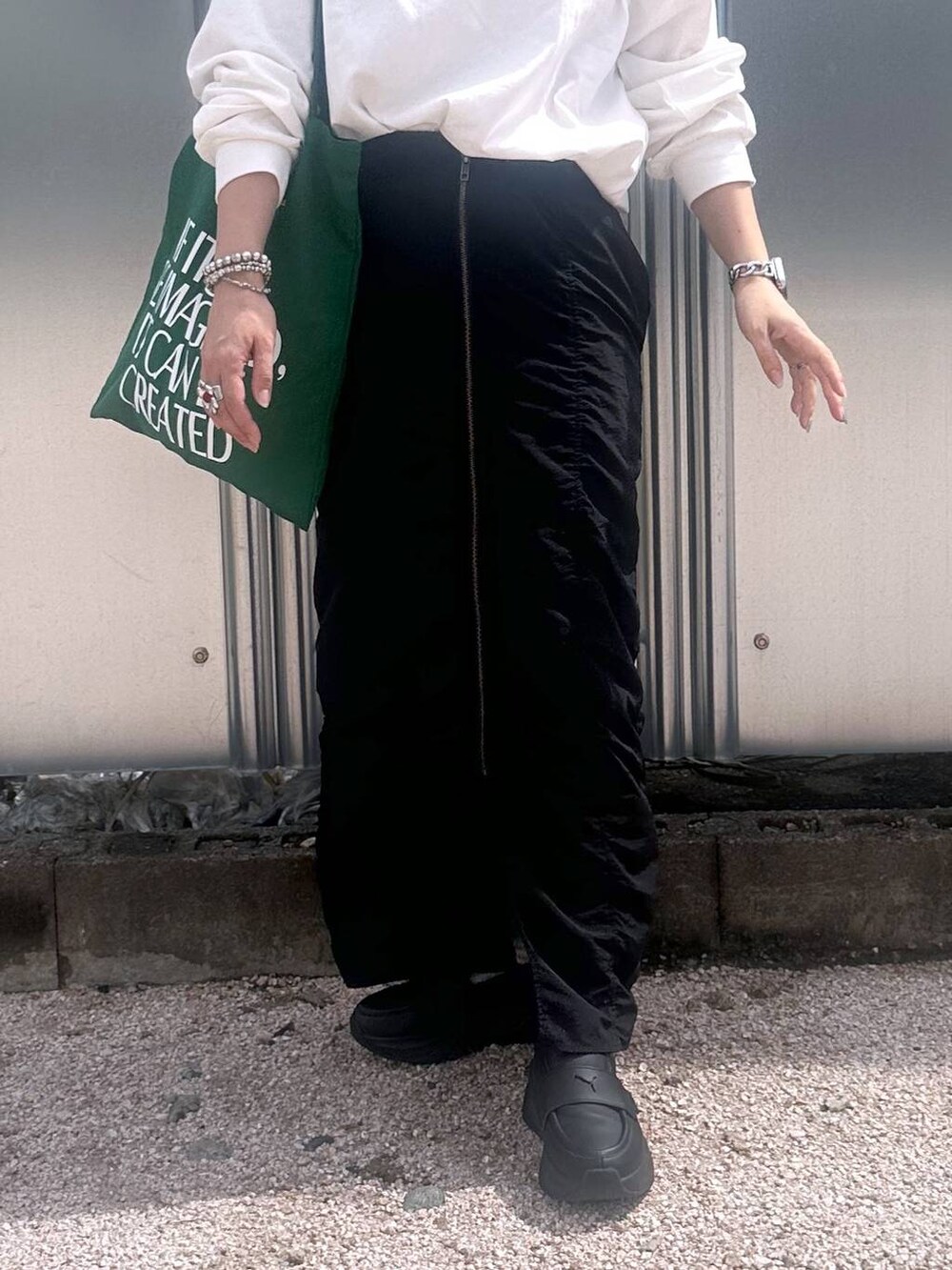 ブラック系のスカート、グリーン系のトートバッグ、その他のピアス(両耳用)を着用したレディースの秋コーディネートの5枚目の写真