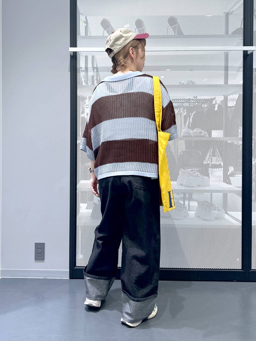 ブラック系のデニムパンツ、イエロー系のトートバッグ、ブルー系のニット/セーターを着用したレディースの春コーディネートの3枚目の写真