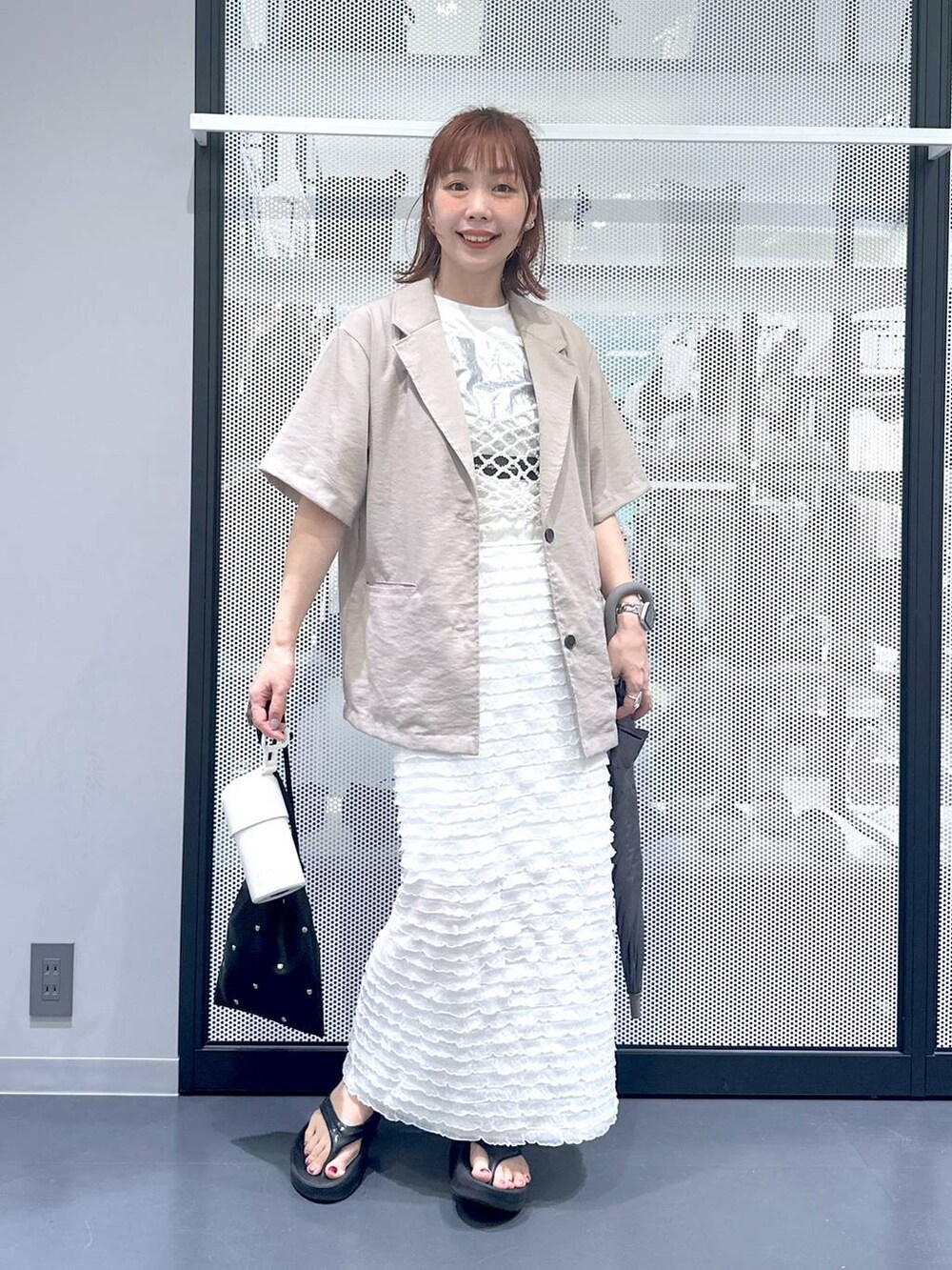 ブラック系のショルダーバッグ、ホワイト系のベスト、ホワイト系のTシャツ/カットソーを着用したレディースの夏コーディネートの3枚目の写真
