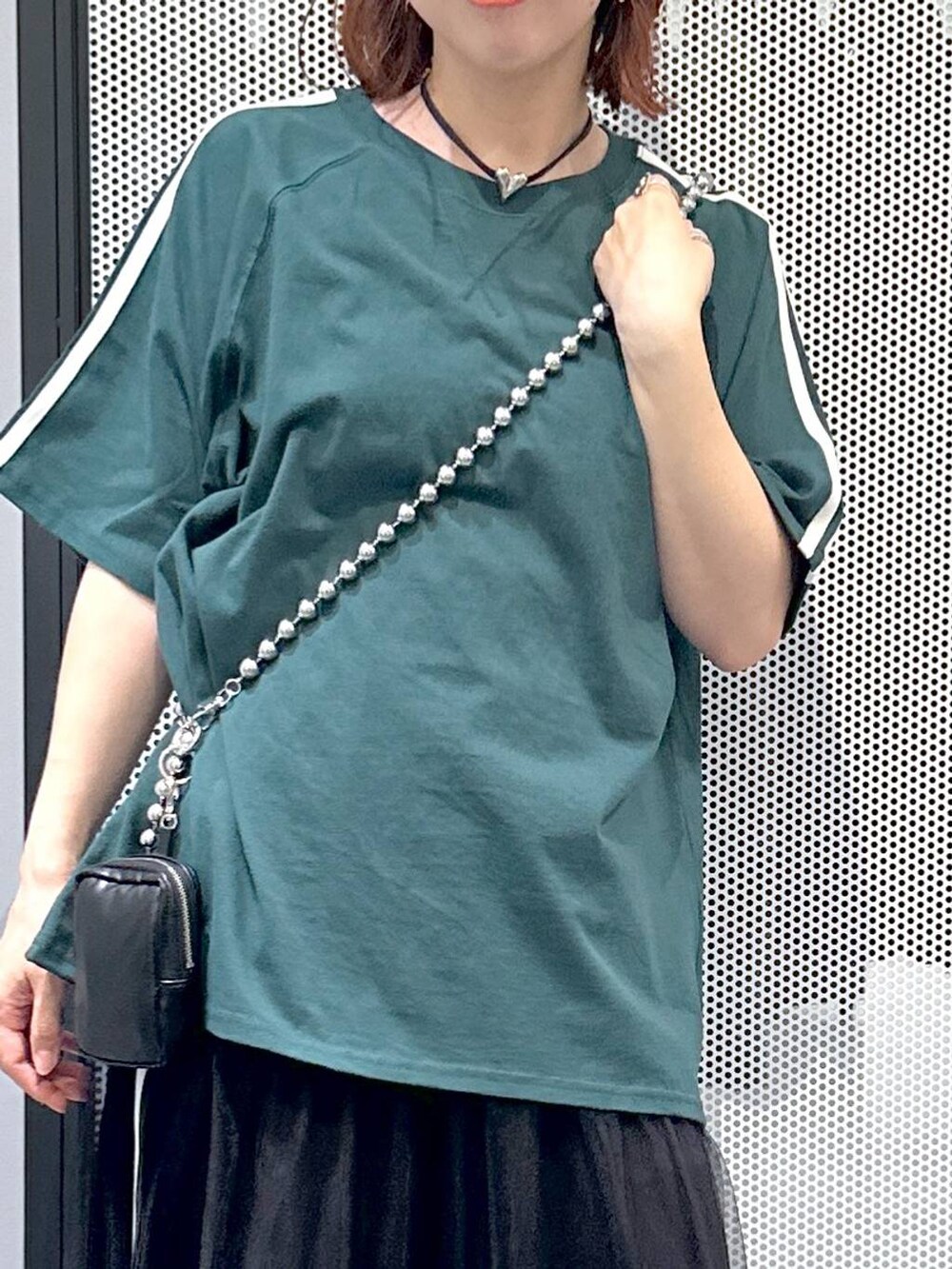 ブラック系のスカート、グリーン系のTシャツ/カットソー、その他のネックレスを着用したレディースの夏コーディネートの4枚目の写真