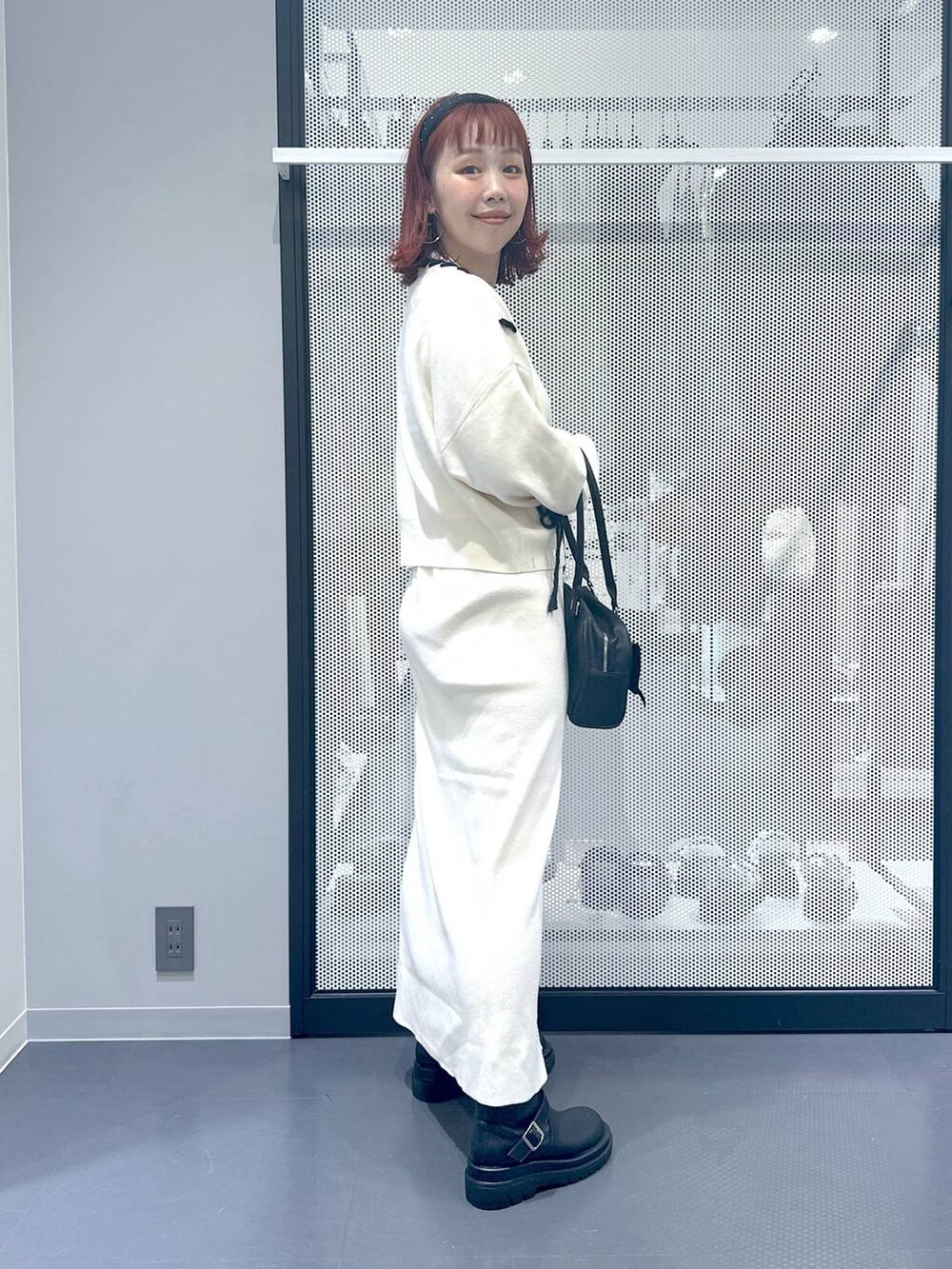 ブラック系のブーツ、ブラック系のハンドバッグ、ベージュ系のスカートを着用したレディースの秋コーディネートの3枚目の写真