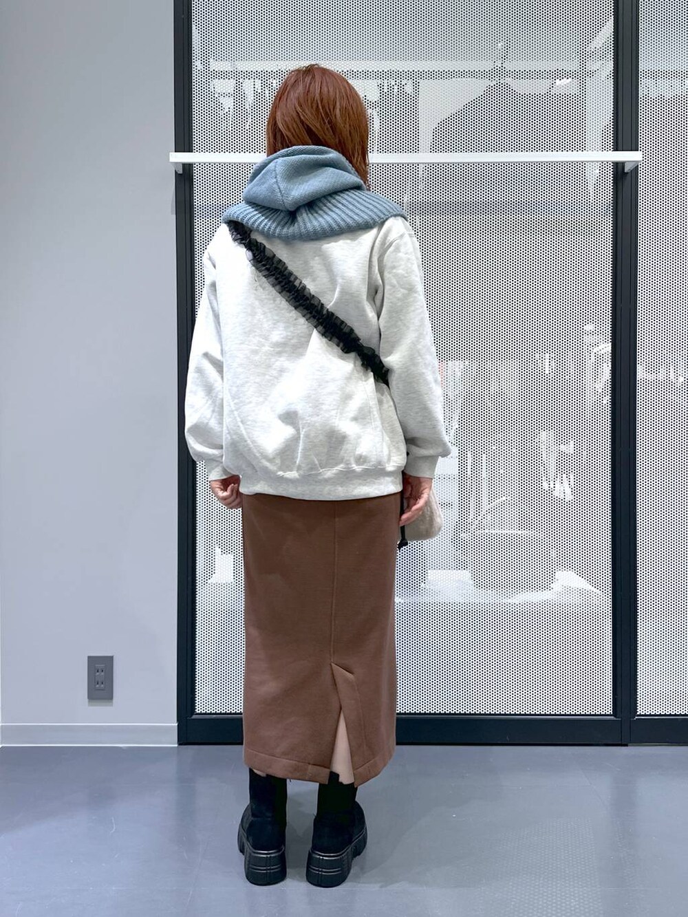 ベージュ系のショルダーバッグ、ブラウン系のスカート、ブラック系のブーツを着用したレディースの冬コーディネートの6枚目の写真