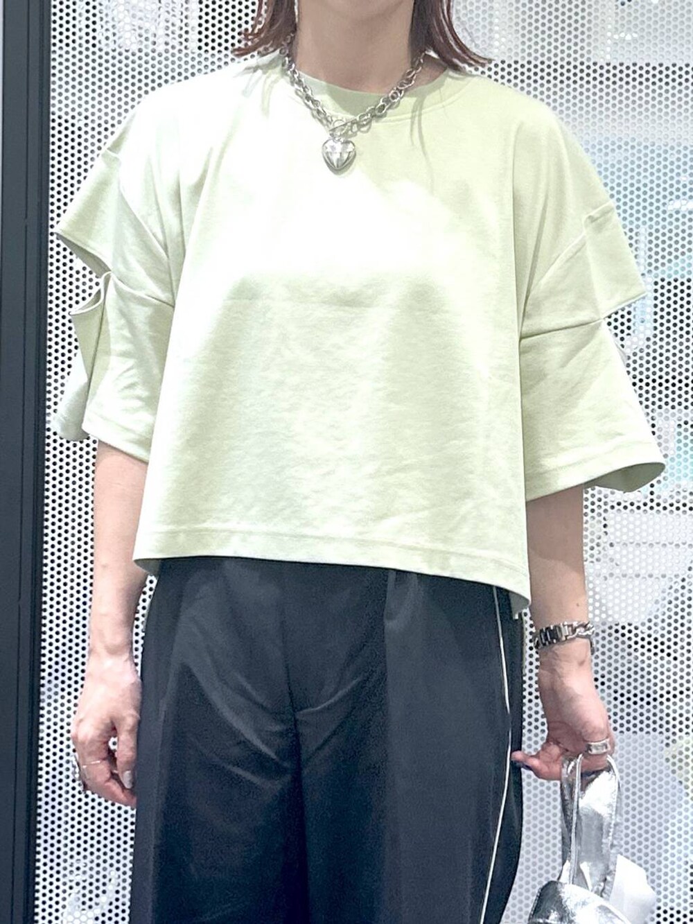 シルバー系のショルダーバッグ、グリーン系のTシャツ/カットソー、ブラック系のサンダルを着用したレディースの夏コーディネートの6枚目の写真